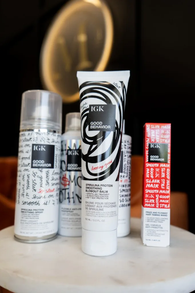 IGK Good Behavior spirulina smoothing balm, smoothing spray, and frizz taming wand on display